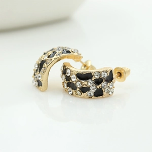 Vue macro de boucles d'oreilles léopard dorées en forme de C avec strass brillants