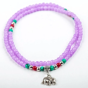 Detailed macro of beaded multilayer bracelet featuring a vintage silver elephant charm