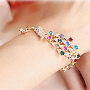 Detailed close-up of a peacock bracelet with colorful rhinestones on a woman's wrist