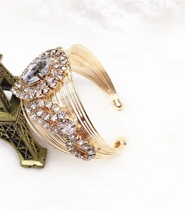 Detailed macro view of a gold-finish multi-wire bangle with a large oval rhinestone cluster