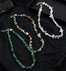 Macro shot of assorted natural stone chip necklaces with silver lobster clasps on black texture