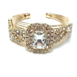 Close-up of golden multi-layer wire bracelet with large rectangular crystal and rhinestones