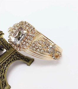 Detailed macro view of gold-tone wire bracelet with large rectangular rhinestone and pave setting