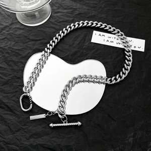 Detail of silver stainless steel Cuban chain with rhinestone T-bar clasp on black background