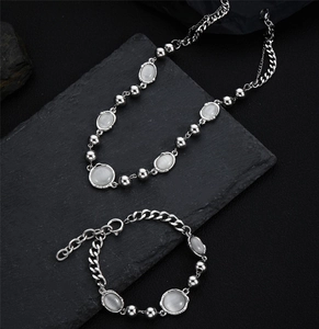Flat lay macro of cat eye stone necklace and bracelet set on dark textured surface