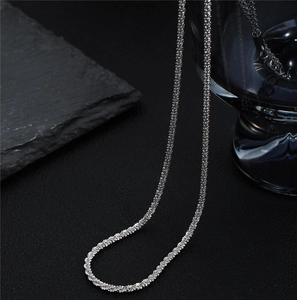 Macro shot of silver titanium steel shimmering chain with intricate twisted texture