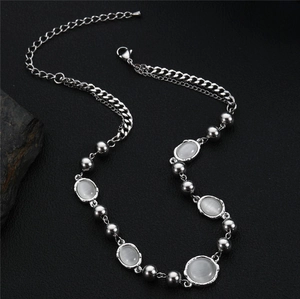 Elegant cat eye stone necklace with silver beads on a textured black background