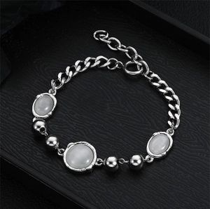 Detail of silver titanium necklace featuring white cat eye stones and polished metal beads