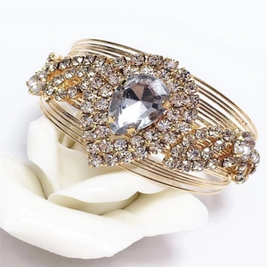 Luxurious gold layered wire cuff bracelet featuring a large teardrop crystal centerpiece