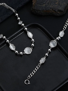 Detail of silver cat-eye stone necklace and bracelet set on black leather texture