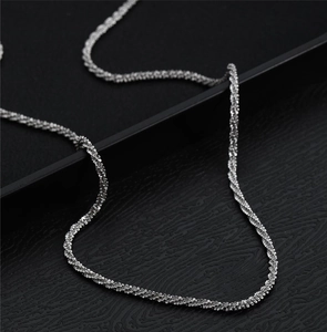 Macro shot of silver titanium steel chain with a textured sparkling spiral weave