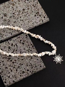 Close-up of vintage sun pendant necklace with bohemian white crushed stone beads