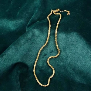 Detail of a sparkling gold popcorn chain necklace displayed on green velvet fabric