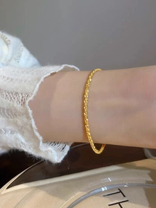 Close-up of sparkling 18K gold twist chain bracelet worn on wrist with elegant texture