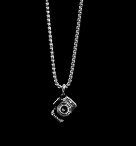 Détail du pendentif appareil photo vintage argenté sur une chaîne à mailles carrées