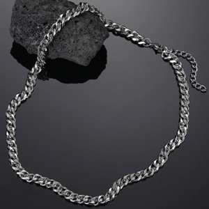 Detail of silver stainless steel Cuban link chain with lobster clasp on volcanic stone