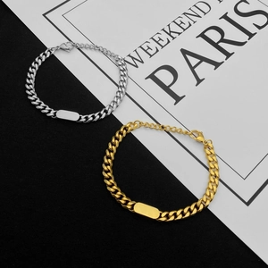 Vista macro di braccialetti a maglia cubana oro e argento con targhette ID lucide