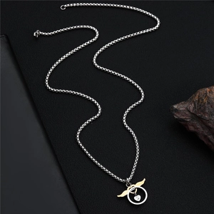 Detailed close-up of heart crystal pendant with gold wings on a silver box chain