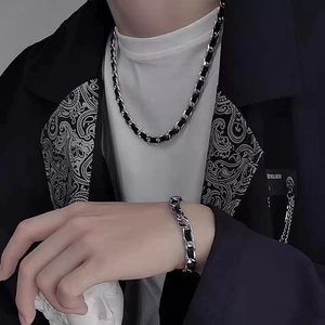 Close-up of titanium steel and black leather braided bracelet and necklace set for men