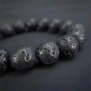 Macro de perles en pierre de lave noire montrant la texture poreuse naturelle et détails
