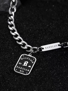 Detail der Silberkette mit schwarzem Good Luck Anhänger und BARDIAN Metallplakette