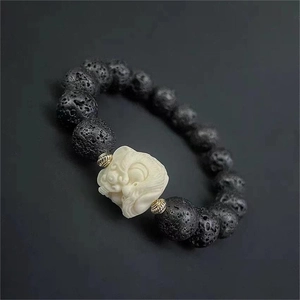 Détail macro d'un bracelet pour hommes en pierre de lave avec un charme Pixiu blanc et or