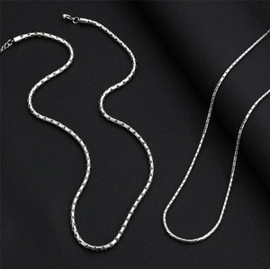 Close-up of titanium steel box chain with lobster clasp on textured black background