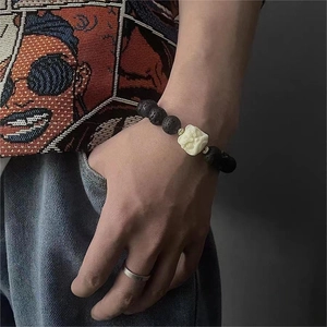 Détail d'un bracelet en pierre de lave avec perle centrale sculptée sur un poignet masculin