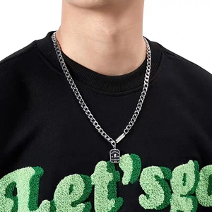 Details einer silbernen Titan-Panzerkette mit gravierter Good Luck Plakette am Kapuzenpullover