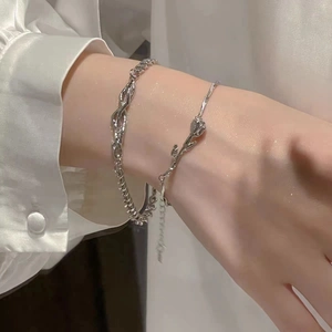 Détail de chaînes en argent avec breloque rose au poignet sur chemise blanche