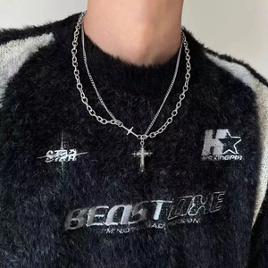 Dettaglio di una collana a doppio strato con pendente a croce su maglione nero