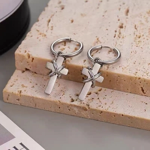 Detail von silbernen Kreuz-Ohrringen mit Drahtwicklung auf minimalistischem Steindisplay