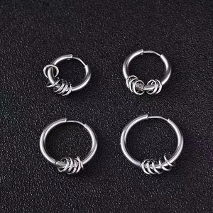 Macro view of silver stainless steel hoop earrings with small charms on black leather