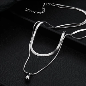 Détail d'un collier double épaisseur en argent avec pendentif goutte d'eau en métal poli