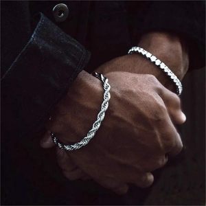 Détail d'une chaîne corde argentée et d'un bracelet tennis sur une veste en jean