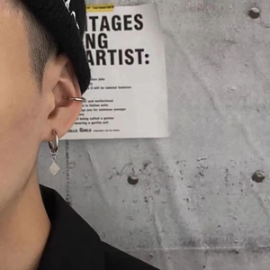 Gros plan d'une boucle d'oreille géométrique en argent poli et d'un faux piercing