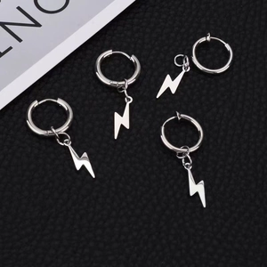 Detalle de pendientes de aro con colgante de rayo plateado sobre cuero negro