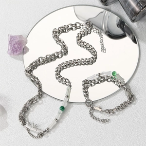 Detail of silver bamboo style necklace and bracelet with green stones on a mirror