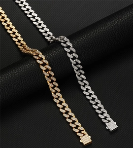 Détail macro des bracelets cubains en argent et or avec zircons sur cuir noir texturé