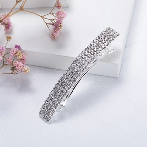Close-up of sparkling silver rhinestone hair clip with spring closure on white surface