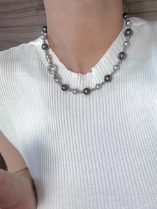 Détail du collier de perles dégradées grises avec fermoir diamanté sur tricot blanc
