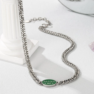 Detail of silver Cuban chain necklace featuring a green enamel BETTER ME letter pendant