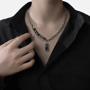Close-up of asymmetric silver chain necklace with black beads and rectangular pendant