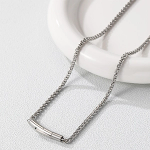 Close-up of a stainless steel dragon bone chain necklace with a polished cylinder pendant