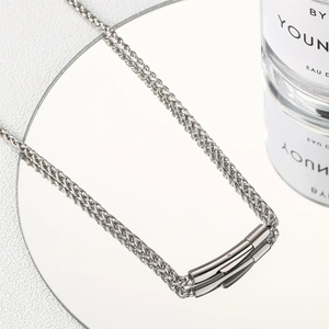 Detailed macro view of woven wheat chain with polished cylinder pendant on mirror