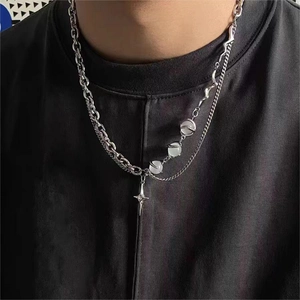 Détail d'un collier multi-rangs en acier avec chaîne croisée, perles d'opale et pendentif étoile