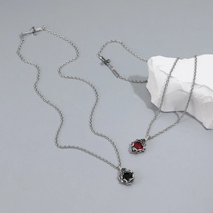 Close-up of vintage rose thorn pendants with red and black gems on silver-toned chains