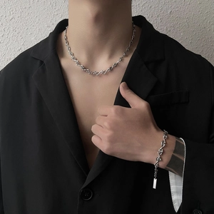 Silbernes geometrisches Titanstahl-Halsketten- und Armband-Set, getragen an einem männlichen Model