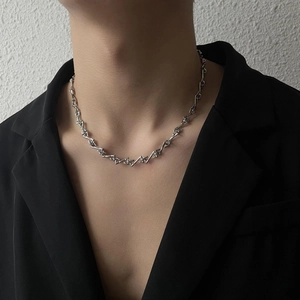 Nahaufnahme der geometrischen silbernen Gliederkette am Modell mit schwarzem Blazer