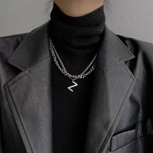 Detail of double-layer stainless steel letter N necklace on a black turtleneck sweater